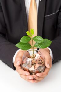 businessman-hand-putting-coins-plant-glass_38810-3292