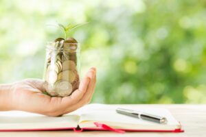 woman-hand-holding-plant-growing-from-coins-bottle_1150-17738